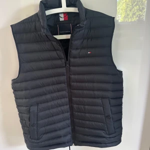 Svart dunväst från Tommy Hilfiger - Köptes helt nya i stockholm tror kvitto kan finnas kvar! Använd fåtal gånger är i nyskick.