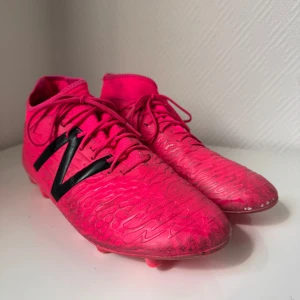 New balance fotbollsskor  - Hej säljer mina fotbollsskor eftersom jag har köpt andra par, men det är New Balance med storlek 45,5 och känns väldigt nya och riktigt coola på plan! Färgen rosa och svart med snören! Är du intresserad är det bara att skriva och vi skickar inom 1-2 dagar