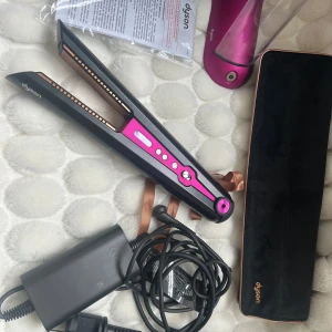 Dyson Corrale plattång svart/rosa - Säljer en oanvänd Dyson Corrale plattång i svart och metallic rosa med kopparfärgade plattor. Kommer med laddare, laddningsstation, värmeskyddande fodral i svart sammet och originalkartong. Perfekt för att styla håret med sladdlös frihet och avancerad teknik. Endast testad 1-2 ggr.