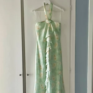 ADOORE - LAMIA HALTERNECK DRESS strl 38 - Säljer denna drömmiga, mintgröna långklänning från Adoore, som tyvärr inte passade min stil. Provad, aldrig använd. Klänningen har halterneck, volang framtill och en elegant slits. Perfekt för sommarens speciella tillfällen. Materialet är lätt och ger en fin siluett. Nypris: 1595kr