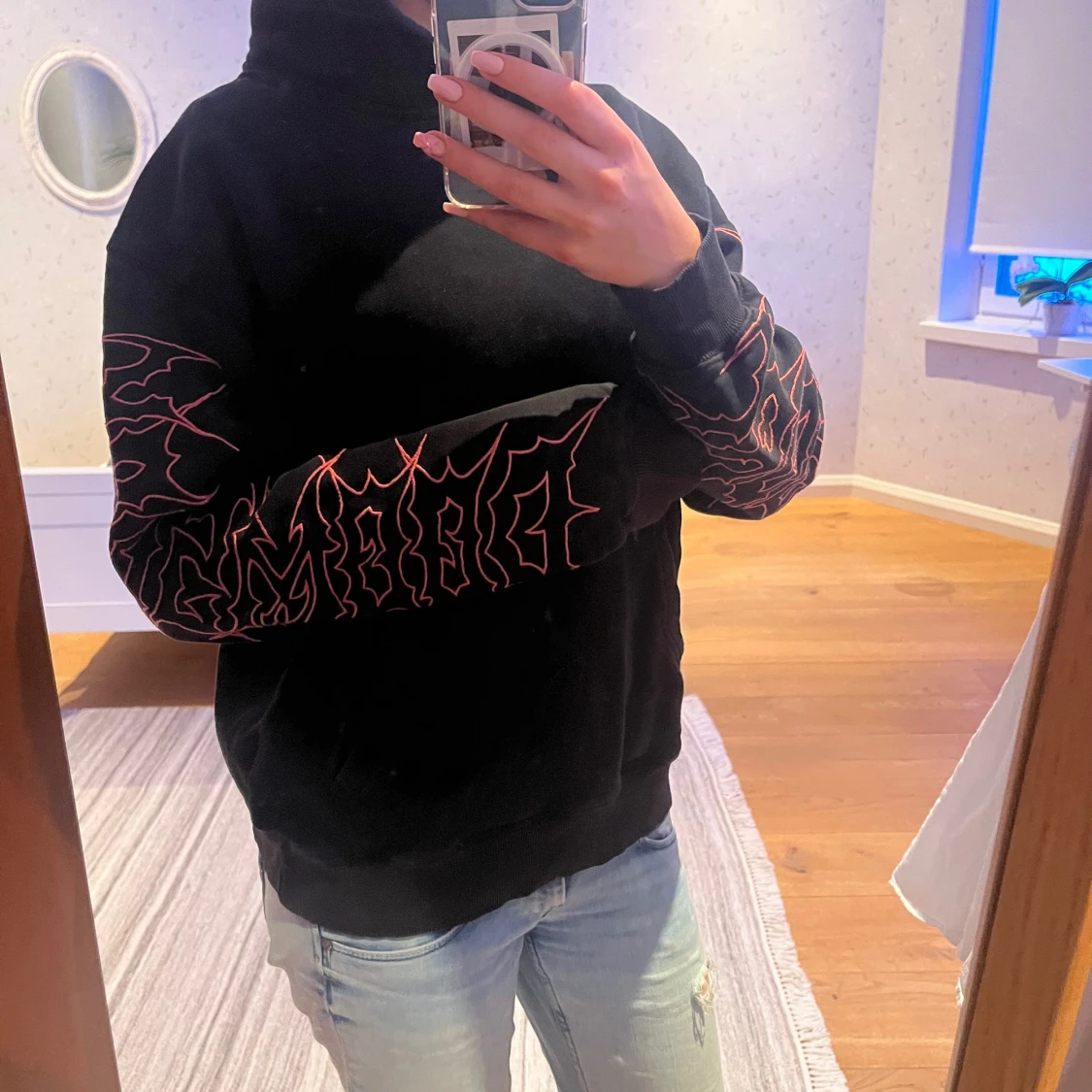 Svart hoodie med röd grafik på ärmar