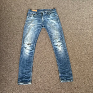 Blå jeansbyxor från Dondup - Säljer ett par sjukt feta blå jeansbyxor från Dondup med slitningar vid knäna och klassisk femficksdesign. Jeansen har normal passform och är tillverkade i denim med lätt tvättad look. Perfekta för en avslappnad stil. Moddeleb är 187 runt 80kg. Modellen heter ritchie och sitter samt ser ut som George modellen. Pris ej hugget i sten, och be gärna om fler bilder eller om ni undrar något. 