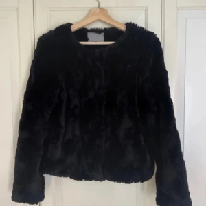 Svart pälsjacka från Vero Moda - Mysig svart pälsjacka från Vero Moda. Jackan har en fluffig och mjuk känsla. Enkel och stilren design som passar till många olika outfits. Kontakta vid frågor eller prisförslag!
