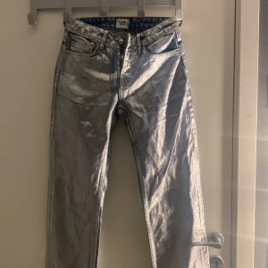 Silvriga jeansbyxor från 157 - Säljer ett par riktigt coola silvriga jeansbyxor från 157. Byxorna har klassisk femficksdesign, normal passform och stängs med knapp. Perfekta för dig som vill sticka ut med en metallic look.