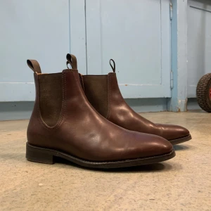 Bruna chelsea boots i skinn - Klassiska bruna chelsea boots i skinn med elastiska paneler på sidorna och rund tå. Var egentligen till min pappa men dem passade inte riktigt! Står ingen storlek i men uppskattar strl. 42😊Har endast testats utomhus en gång! 