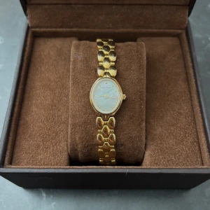 Guldfärgad Certina damklocka - Elegant guldfärgad damklocka från Certina med ovalt ur och länkarmband i metall. Urtavlan är ljus med diskreta markeringar och klockan har en klassisk, tidlös design. Perfekt accessoar för dig som gillar stilrena detaljer.