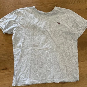 Ljusgrå t-shirt från GANT - Säljer en ljusgrå t-shirt från GANT med liten broderad logga på bröstet. Klassisk passform och rund halsringning. Perfekt till vardags och enkel att matcha med det mesta.