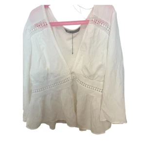 Vit blus med spetsdetaljer från Zara - Superfin vit blus från Zara med v-ringning och snygga spetsdetaljer på axlar och midja. Blusen har lång ärm, lätt volang nertill och är gjord i ett tunt, luftigt bomullstyg. Perfekt för sommaren. Passade inte mig så bra. Storlek XL men passar som L.  Använd 3 gånger💞💞