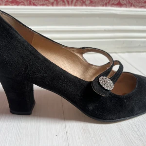  italienska klackskor i mocka - Säljer ett par eleganta svarta klackskor i mocka med rund tå och diamant detalj. Skorna har en klassisk lite tjockare klack och är tillverkade i Italien. Storlek 36, bra skick! Skriv vid intresse💕