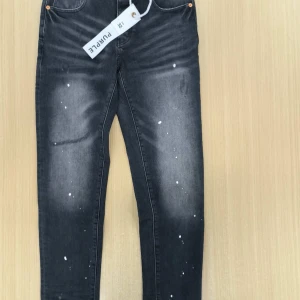 Svarta jeans från Purple Brand - Snygga svarta jeans från Purple Brand med coolt stänkmönster i vitt och slitna detaljer. Jeansen har klassisk femficksdesign, raka ben och knappgylf. Perfekta för dig som gillar streetwear och vill sticka ut lite extra.