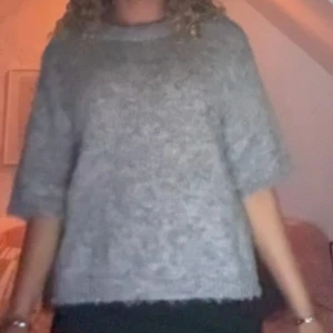 Grå stickad tröja med halvärm - Mysig grå stickad tröja med lite lös passform och halvärmar. Perfekt för lager-på-lager och chill dagar. Tröjan har en enkel rund halsringning och är fluffig i materialet, vilket ger en soft vibe. Skriv vid fler frågor💗