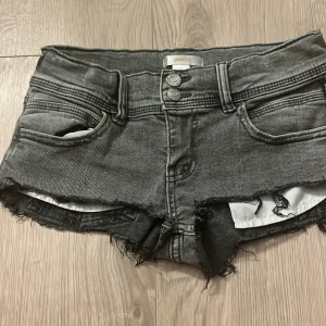 Grå jeansshorts med silverstjärna Gina Tricot - Snygga grå jeansshorts som i grunden är jeans från Gina Tricot, fransiga kanter och dubbla knappar framtill. På ena bakfickan finns en silverfärgad stjärna som detalj. Klippta själv och dom passar helt perfekt, använda runt 5 gånger