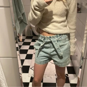 Ljusblå  jeansshorts  - Snygga ljusblå  shorts i jeans från Lindex med knytskärp. De har avslappnad passform, rynkad midja och uppvikta benslut. Perfekta för varma dagar och ger en cool vibe till din outfit.
