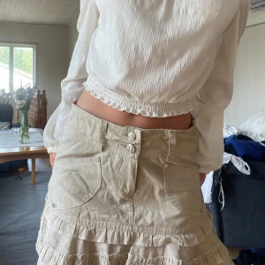 Beige kjol - Supersöt beige tubtopp eller kjol beroende på hur man bär den med volanger och dekorativa fickor framtill. Kjolen har dubbla knappar och resår upptill som jag trätt in själv! Köpte på en fransk marknad för 30€ så vet inte vad det är för märke💓💓Kan skicka fler bilder privat! Står ju storlek S i kjolen men jag skulle snarare säga xs-s