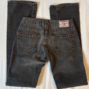 Vintage Y2K True Religion jeans med låg midja - Äkta Y2K True Religion jeans köpta på 2000-talet i grå färg. Låg midja, midjemått mätt rakt över ca 36-37 cm. Långa ben, innerbenslängd 86 cm. Oanvända utan defekter. Hör av dig vid frågor, öppen för prisförslag 💕