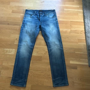 Blå slim fit jeans från Jack & Jones - Snygga blå jeans från Jack & Jones i modellen Slim Fit Glenn. Tillverkade i mjukt bomullstyg med stretch för extra komfort. 