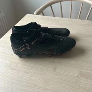 Svarta fotbollsskor från Puma - PUMA FUTURE 7 ULTIMATE LÅG FG/AG ECLIPSE - SVART/KOPPARROS