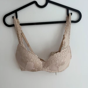 Beige spets bh med vaddering - Säljer en beige push up bh med vadderade kupor och breda axelband. Missfärgning på insidan men inget som syns utanpå! Även några få trådar som sticker fram från broderingen men inget märkbart🤍