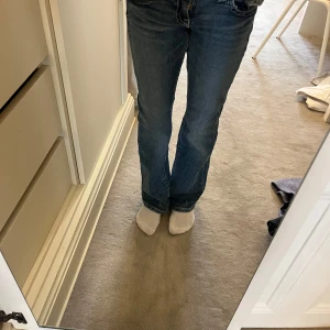 Blå bootcut jeans från Gina Tricot - Snygga blå jeans från Gina Tricot i storlek 152. Modellen har bootcut-ben och klassisk femficksdesign. Jeansen är i ett mjukt denimtyg och har normal passform med midwaist. Perfekta till sneakers eller boots.