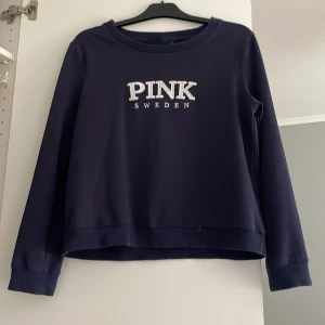 Mörkblå sweatshirt från Pink Sweden - Mörkblå sweatshirt från Pink Sweden med broderad vit logga på bröstet. Storleken är L men passar mig bra som är S-XS. 