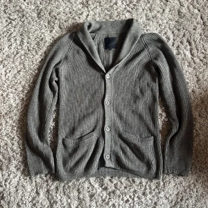 Grå stickad cardigan  - Säljer denna snygga stickade cardiganen i en ull blend från Blue Print. Den är i bra skick utan defekter och är i storlek L. Bara att skriva över frågor och funderingar.
