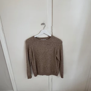 Beige stickad tröja med rund hals - En enkel och stilren beige stickad tröja med rund halsringning och långa ärmar. Tröjan har ribbade muddar vid ärmslut och nederkant, perfekt för lager-på-lager under kyliga dagar använd ganska många gånger men inga tecken på använd.