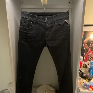 Mörkblå Replay jeans straight fit - Snygga mörkblå jeans från Replay med klassisk femficksdesign och raka ben. Jeansen har tydliga Replay-detaljer vid fickan och röd etikett på insidan. Tillverkade i slitstarkt denimtyg med kontrastsömmar för en clean look. Aldrig använd. W33