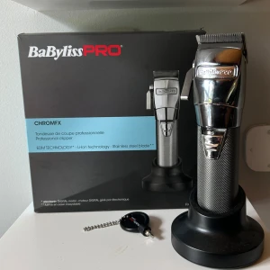 BaBylissPRO CHROMFX hårtrimmer - Snygg och robust clipper från BaBylissPRO i modellen CHROMFX. Clippern har ett greppvänligt handtag i silverfärgad metall och blanka detaljer i rostfritt stål. Har endast använts ett fåtal gånger. Levereras med laddningsställ och originalförpackning.