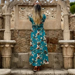 Turkos blommig långklänning med volang - Superfin turkos långklänning med blommigt mönster i vitt och brunt. Klänningen har v-ringning, volangdetaljer vid axlarna och är ärmlös. Den har en markerad midja och ett luftigt fall, perfekt för varma dagar.Använd bara en gång Storlek passar både M och L