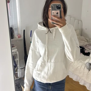 Vit hoodie från FB Sister XS - Vit hoodie från New Yorker i storlek XS. Klassisk modell med huva, snörning och stor magficka framtill. Mjuk och skön, perfekt till jeans eller leggings. Långärmad och i enkel stil som funkar året runt.