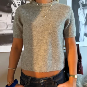 Grå stickad kortärmad tröja Zara - Mysig grå stickad tröja med korta ärmar och rund hals. Super populär tröja från Zara som inte går att köpa längre. Tröjan har en enkel och stilren design med ribbade kanter vid ärmslut och nederkant. Perfekt att matcha med jeans. 