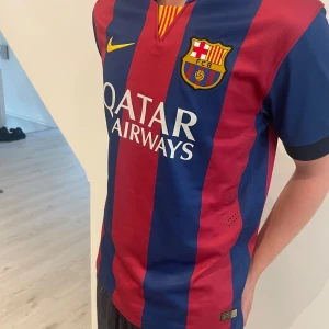 FC Barcelona Neymar 11 fotbollströja - Klassisk FC Barcelona matchtröja med Neymar 11 på ryggen. Tröjan är blå och röd med gula detaljer, har klubbmärke och Nike-logga på bröstet samt Qatar Airways som sponsor. Kortärmad modell i lätt och ventilerande material.