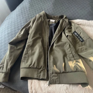 Olivgrön bomberjacka från Urban W. Aid - Säljer en olivgrön bomberjacka från Urban W. Aid. Jackan har dragkedja framtill, ribbade muddar vid ärmslut och midja samt en klassisk bomberjacke-passform. Perfekt för vår och höst Passar XS!!💕💕😇.