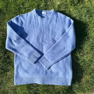 Blå stickad tröja med rund hals - Mysig blå stickad tröja med rund halsringning och ribbade muddar vid ärmslut och nederkant. Perfekt för kyligare dagar och enkel att matcha med olika outfits. Står 164 cm i tröjan men den sitter som S/M