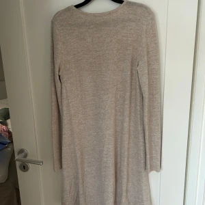 Beige stickad långärmad klänning från Bik Bok - Mysig beige stickad klänning från Bik Bok med lång ärm och rund halsringning. Perfekt för kyligare dagar och enkel att styla med boots eller sneakers.