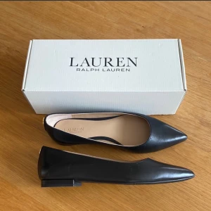 Lauren Ralph Lauren Ballerinaskor, Svarta, EUR 39 - Eleganta svarta ballerinaskor från Lauren Ralph Lauren. Skorna har en tidlös spetsig tå och en elegant låg klack – perfekta både till vardags och till festligare tillfällen. Levereras i originalkartong.  Skorna är märkta som storlek 39, men de upplevs som små i storleken och kan passa dig som brukar ha 38 eller 37,5.  Skorna är helt oanvända. Jag säljer dem då jag ångrade mitt köp och  hittade ett annat par som kändes mer rätt för mig.  Pris går att diskutera vid snabb affär :)
