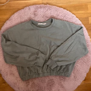 Baby grön croppad sweatshirt från lager 157 - Säljer en enkel och stilren baby grön croppad sweatshirt från lager 157. Tröjan har rund halsringning, långa ärmar och resår i midjan samt vid ärmsluten. Perfekt för en avslappnad look.