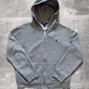 Ralph Lauren Hoodie/Zipper - Snygg Ralph Lauren Hoodie, perfekt till våren. Bekvämt och tungt material, känns verkligen som premium.  Väldigt fint skick 🌟 100% Äkta  ✅  Mått 📏  Storlek: L Youth ≈ Storlek XS vuxen Bredd: 52 Längd: 60 Ärm: 54  Enda anmärkningen är att det finns en liten knappt synlig fläck vid märket på bröstet, som syns i 3e bilden.  A54