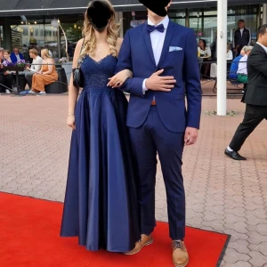 Mörkblå långklänning med spetsdetaljer & fickor - Marinblå balklänning storlek S/M Använd 1 gång och fint bevarad Har inbyggda fickor, så slipper man väska.                 Säljer en elegant mörkblå långklänning med vacker spets upptill och smala axelband. Klänningen har en vid kjol i satinliknande material och fina broderade detaljer på livet. Perfekt för bal eller fest.