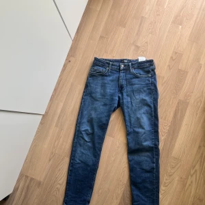 Blå jeans Regular Clark från Jack & Jones - Säljer ett par klassiska blå jeans från Jack & Jones, modell Regular. Normal passform och stängs med dragkedja och knapp. Perfekta för dig som gillar en tidlös stil. 30 midja 30 längd