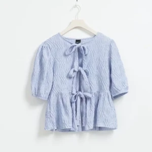 Ljusblå blus med knytband - Supersöt ljusblå blus med tre knytband framtill och lätt puffade ärmar. Perfekt för vår och sommar!