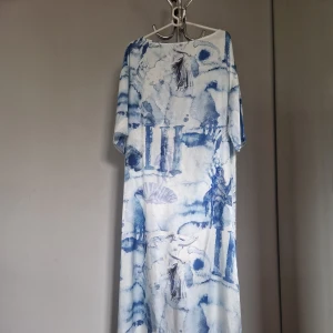 Blåvit långklänning från NA-KD - Säljer en långklänning från NA-KD med unikt blåvitt mönster som påminner om akvarell. Klänningen har lös passform, trekvartsärm och rund halsringning. Perfekt för sommarens tillfällen när du vill sticka ut med en konstnärlig look.