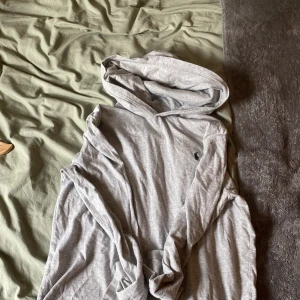 Grå hoodie från Polo Ralph Lauren - Säljer en klassisk grå hoodie från Polo Ralph Lauren i storlek L. Tröjan har huva och är tillverkad i mjuk bomull, perfekt för en avslappnad stil. Liten broderad logga på bröstet. Passar till många tillfällen!
