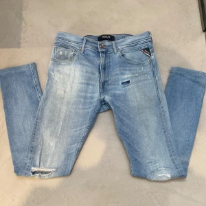 ljusblå Replay jeans - Säljer ett par Replay Jondrill jeans i ljusblå tvätt med riktigt sköna slitningar perchelt för sommaren. Dem är slim fit och i bra skick. Tveka inte på att höra av er vid frågor samt funderingar.