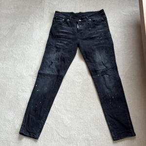 Svarta skinny jeans från Gallery Dept. - Svarta jeans från Dsquared2. med skinny passform och unika vita färgstänk. Klassisk femficksmodell med dragkedja och knapp. Bak finns en vit patch med röd och svart grafik samt texten 'I LOVE YOU'. Perfekta för en edgy streetstil.