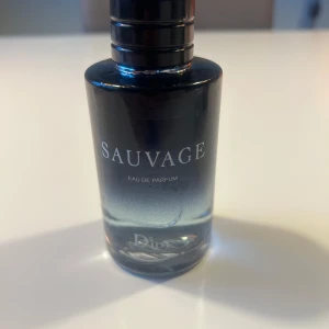 Sauvage Eau de Parfum från Dior 100ml - Säljer en lyxig herrparfym, Sauvage Eau de Parfum från Dior. Flaskan är elegant i mörkblått glas med silverdetaljer och rund form. Doften är intensiv och maskulin, perfekt för dig som vill sticka ut.          Använd ett fåtal gånger, cirka 90ml kvar