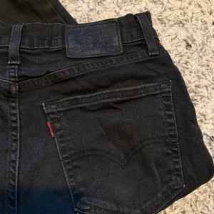 Svarta Levi's Premium jeans - Säljer ett par svarta Levi's Premium jeans med klassisk femficksdesign och rakt snitt. Jeansen har en diskret röd Levi's-tag på bakfickan och svart patch bak i midjan.  Storleken är : W30 L-30