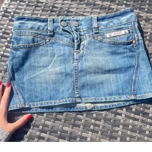 Jeanskjol från Herrlicher - Säljer en klassisk blå jeanskjol från Herrlicher med fem fickor och dubbla knappar framtill. Kjolen har en kort passform och tydliga jeanssömmar. Perfekt för dig som gillar en tidlös denimlook.