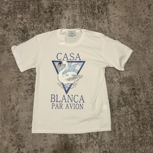Vit t-shirt med svan och blått tryck från Casablanca - Vit t shirt med ett skönt svan tryck på framsidan. Säljer för den var lite för stor för mig. Storleken är L och märket är CasaBlanca 
