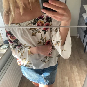 Offshoulder blommig blus i vitt - Säljer en superfin offshoulder blus i vitt med blommigt mönster i rosa, rött och grönt. Vida ärmar och luftig passform, perfekt för vår och sommar. Snygg till både jeans och kjol! 🌸